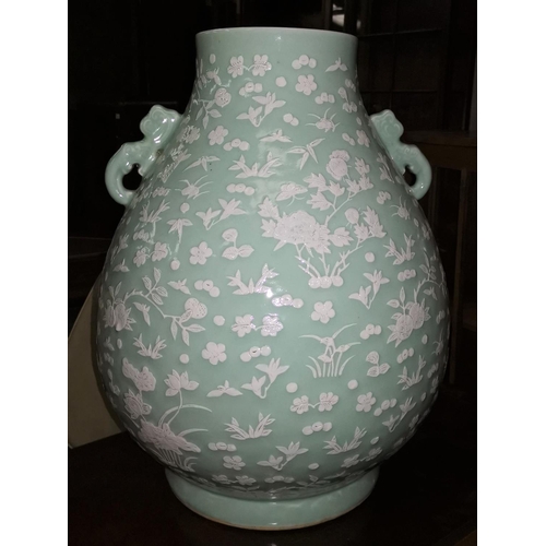 124 - A very large Chinese ceramic vase with celadon glaze and raised white floral and naturalistic decora... 