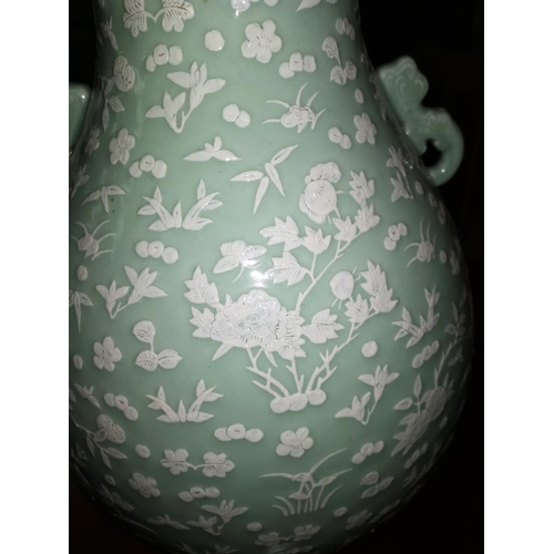 124 - A very large Chinese ceramic vase with celadon glaze and raised white floral and naturalistic decora... 