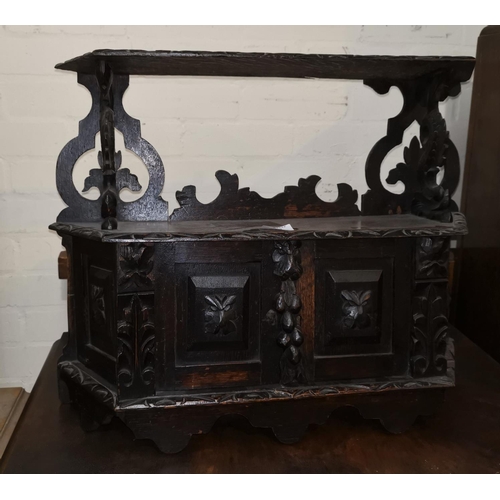522 - A small carved dark oak wall hanging sheld with double cupboard under