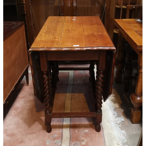 559 - A 1930's golden oak drop leaf dining table with canted and scalloped top, on barley twist legs