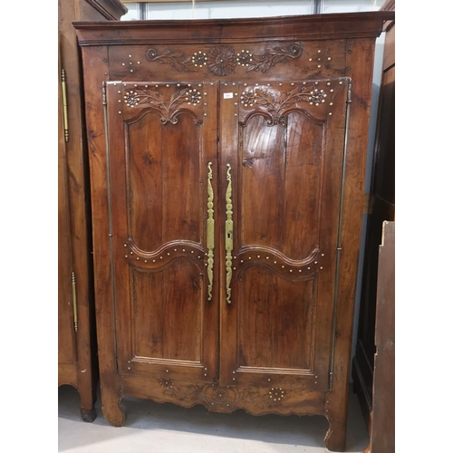 645 - An 19th century French Provincial carved chestnut armoire enclosed by 2 panelled and brass studded d... 