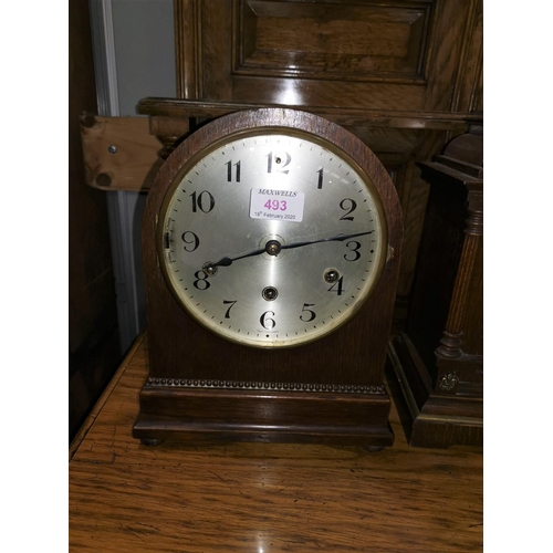 493 - An oak cased mantel clock with arch top, reeded decoration and silvered dial