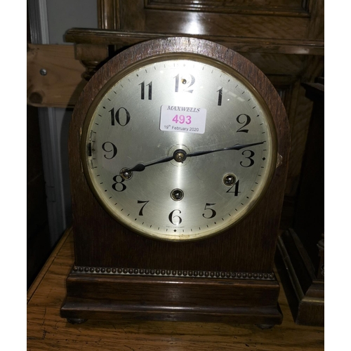 493 - An oak cased mantel clock with arch top, reeded decoration and silvered dial