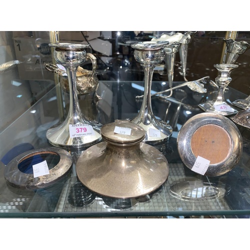 379 - A silver capstan inkwell; a pair of silver candlesticks (loaded); a pair of small circular frames