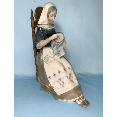 137 - A Lladro figure of a seated girl with embroidery, 28cm (thumb a.f.)