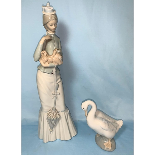 139 - A Lladro girl in long dress holding a Pekinese and a Lladro goose