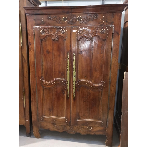 592 - An 19th century French Provincial carved chestnut armoire enclosed by 2 panelled and brass studded d... 