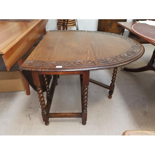 568 - An early 20th century oak drop leaf occasional table with carved oval top, on barley twist legs