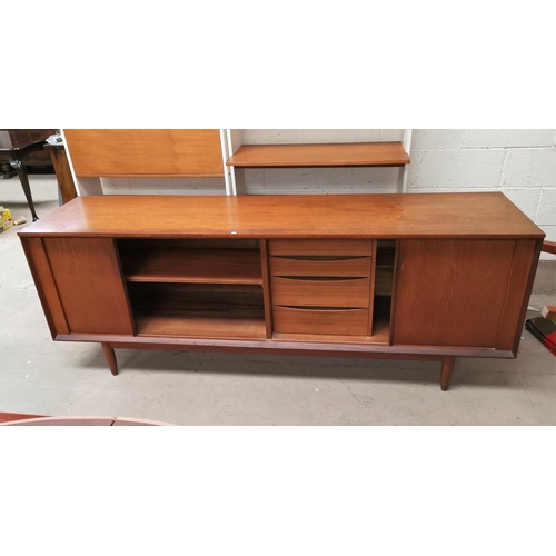 575A - A 1960s teak long low line sideboard with tambour doors with four central drawers two with cutlery c... 