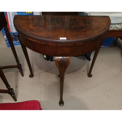 617 - A reproduction crossbanded figured walnut fold over demi-lune card table with green baize lining