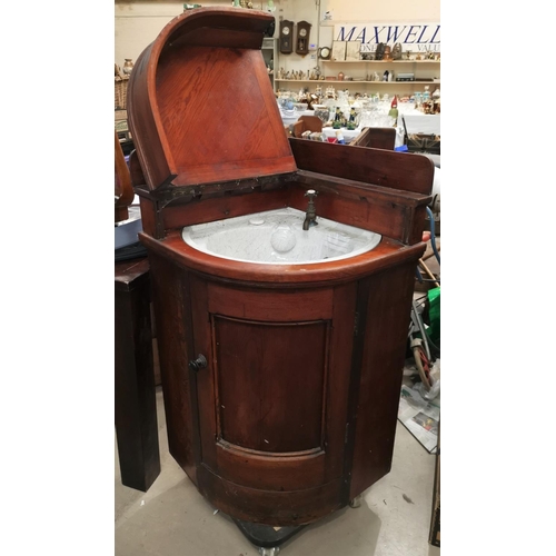 653 - A Victorian pitch pine case corner unit fitted with a ceramic washbasin, hinged lid and door, in the... 