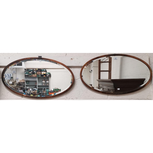 370 - An early 20th century pair of bevelled edge wall mirrors in oval copper frames; a copper fondue pot;... 