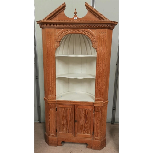 592 - A full height stripped pine corner cupboard in the Georgian style, with arched pediment, open shelve... 