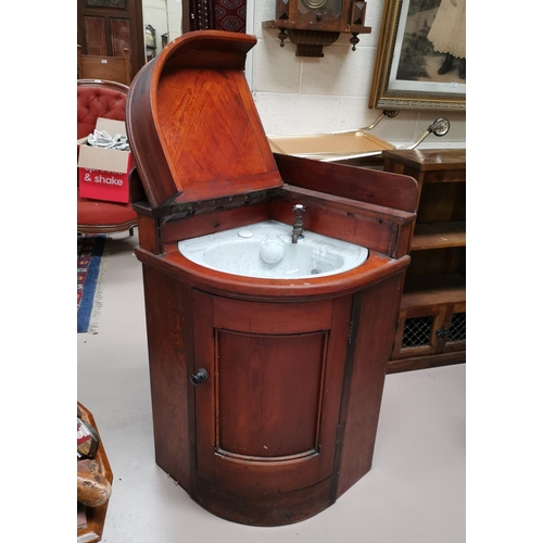 683 - A Victorian pitch pine case corner unit fitted with a ceramic washbasin, hinged lid and door, in the... 