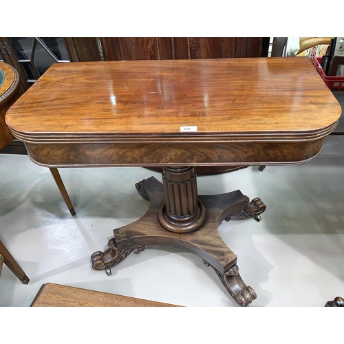 629 - An early 19th century mahogany fold-over tea table on reeded column and quatrefoil base, with scroll... 