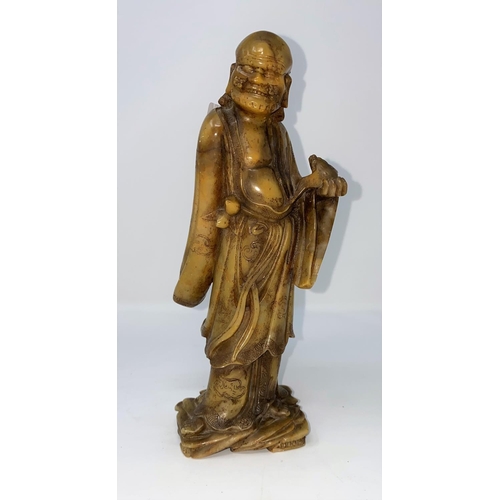 309 - A Chinese soapstone carving of man in cloud robes, holding a bat like creature