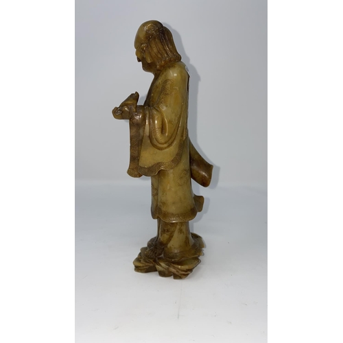 309 - A Chinese soapstone carving of man in cloud robes, holding a bat like creature