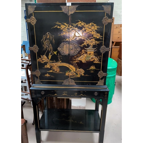 351 - An early 20th century oriental cabinet on stand, black lacquered with gilt decoration of bridge and ... 