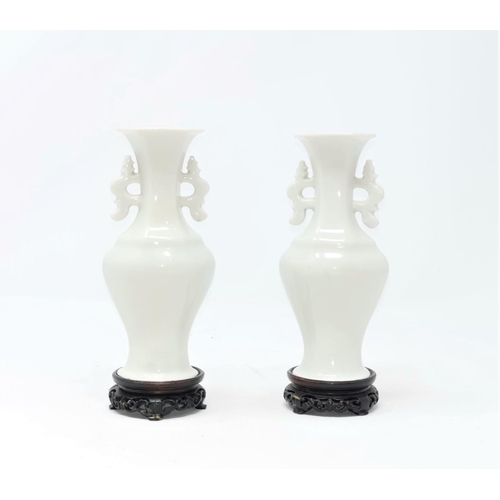 319A - A pair of Chinese blanc de chine vases on wooden stands with double handles, 14cm