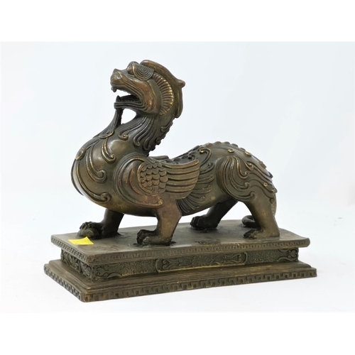 324A - A Chinese bronze sculpture of a mythical winged beast on a plinth length 17cm