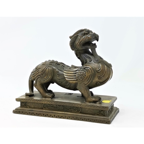 324A - A Chinese bronze sculpture of a mythical winged beast on a plinth length 17cm