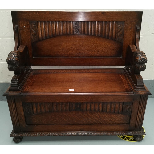 645 - An oak monks bench with panelled decoration and grape carving, lion arm supports, on bun feet, lengt... 