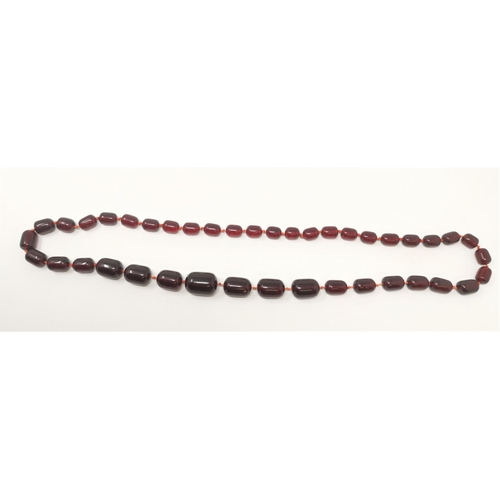 457 - A cherry amber coloured necklace with clear ovoid shape beads, largest bead 2.5cm, overall length 80... 
