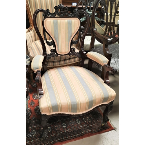 564 - A late Victorian dark mahogany armchair with extensive carved decoration and cabriole legs in stripe... 