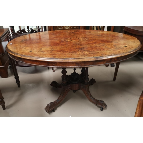 659 - An oval Victorian figured walnut and marquetry quarter veneered looe table on 4 turned columns and 4... 