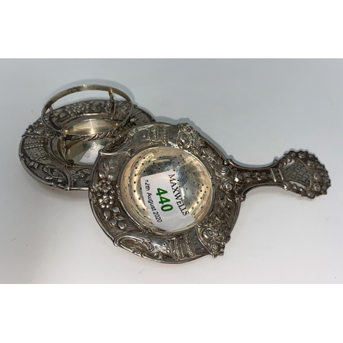 440 - A continental white metal tea strainer and stand heavily embossed with cornucopia and flowers empres... 