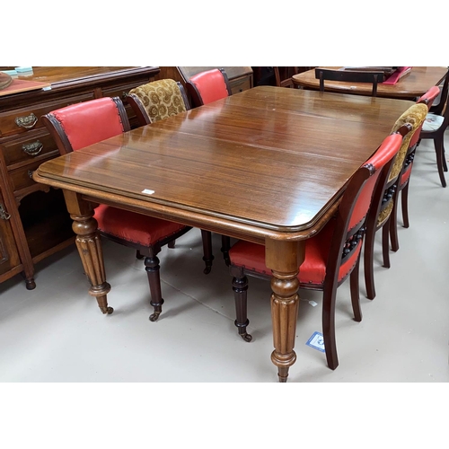 520 - A Victorian mahogany wind-out dining table, on tapering reeded legs and castors, 1 spare leaf, with ... 