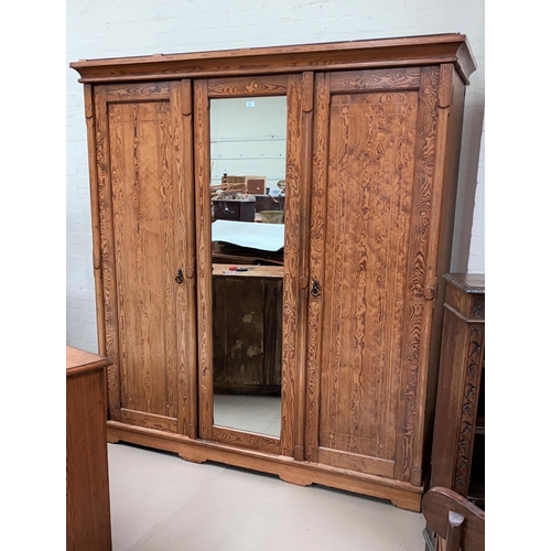 521 - A Victorian pitch pine triple wardrobe wit central mirror and panelled side doors