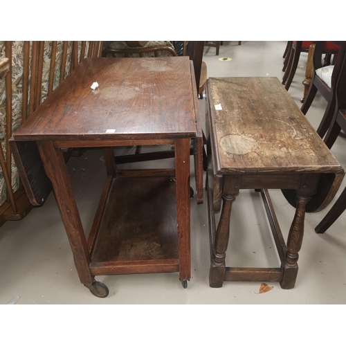 509 - A small oak coffee table with oval drop leaf top; an oak 2 tier tea trolley with drop leaf