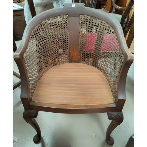 605A - An early 20th century bergère armchair in stained walnut, on cabriole legs