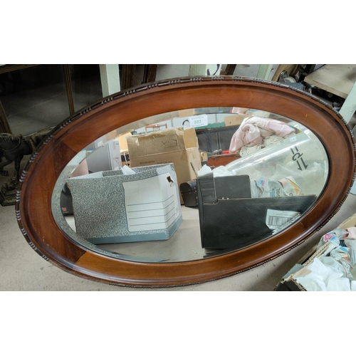 593 - A 1920's oval wall mirror in mahogany frame