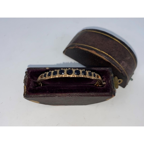 276 - An Edwardian 9 carat hallmarked gold hinged filigree bangle, set 9 oval graduating sapphires, 15.4 g... 