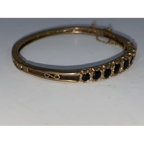 276 - An Edwardian 9 carat hallmarked gold hinged filigree bangle, set 9 oval graduating sapphires, 15.4 g... 