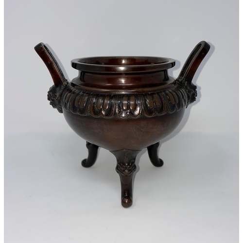 84 - A 19th century Chinese bronze incense burner, cauldron shaped with facemask side handles and 3 scrol... 