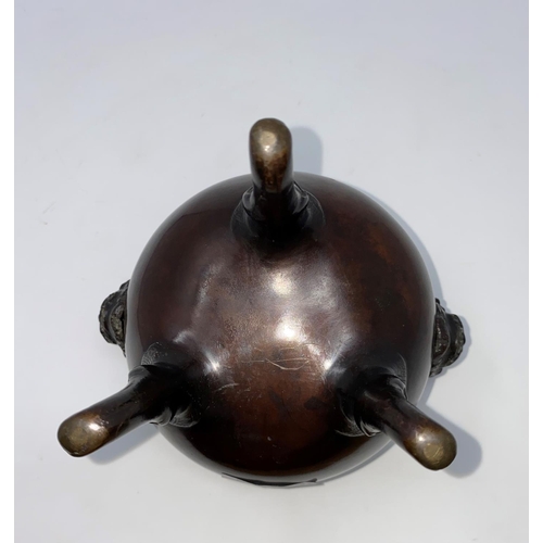 84 - A 19th century Chinese bronze incense burner, cauldron shaped with facemask side handles and 3 scrol... 