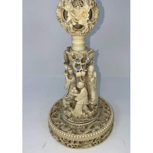 97 - A 19th century carved ivory puzzle ball on stand with base of carved dragons, the pillar with figure... 
