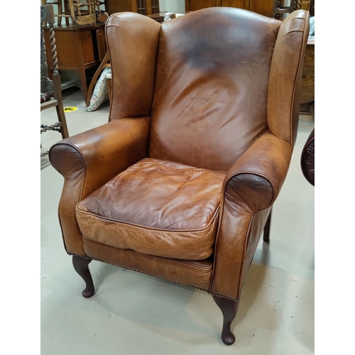 538A - A traditional style wing backed armchair in tan hide