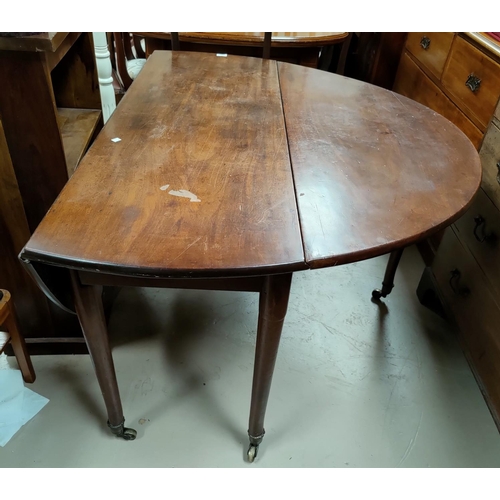 557A - A Georgian mahogany dining table with oval drop leaf top, on turned legs and castors, 140 cm