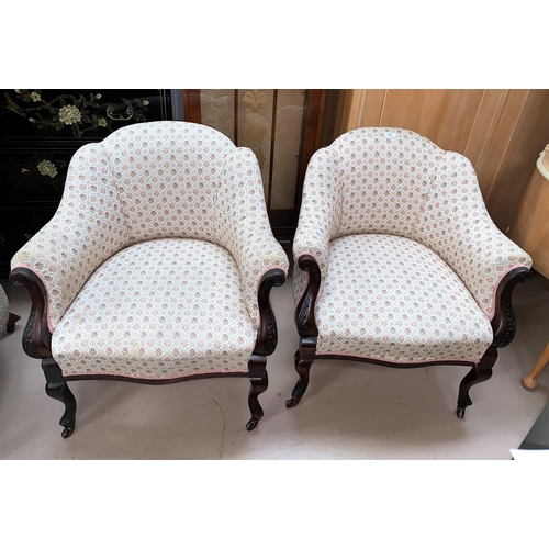 576 - A pair of Edwardian carved mahogany tub shaped armchairs, reupholstered in floral print Damask, on c... 
