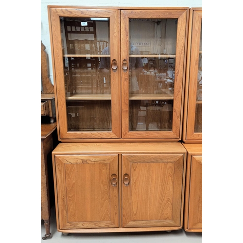 599 - An Ercol light elm full height side cabinet with 2 shelves enclosed by glazed doors, cupboards under... 