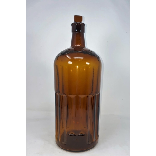 115A - A vintage ribbed brown glass bottle marked 'POISON' in relief, with glass stopper, height 37cm
