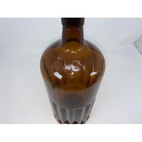 115A - A vintage ribbed brown glass bottle marked 'POISON' in relief, with glass stopper, height 37cm
