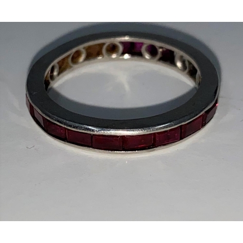 374 - A white metal eternity ring set rectangular cut rubies, 4.1 gm. Size P. (two loose stones)