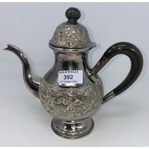 392 - A white metal coffee pot with extensive embossed decoration, tests as silver