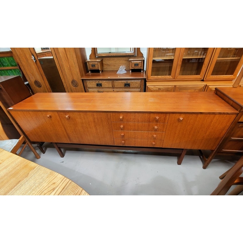540 - A mid-20th century teak long low sideboard, comprising: cupboard to each end, a full front compartme... 