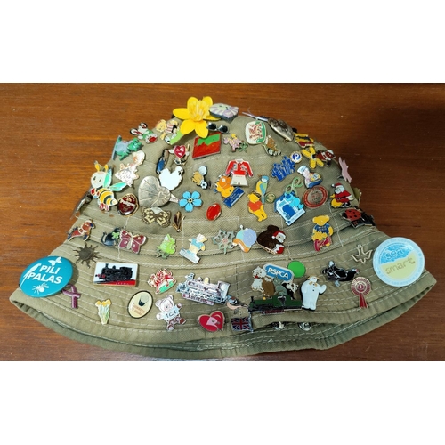 132 - A selection of vintage badges and pins attached to canvas hat (on behalf of charity)